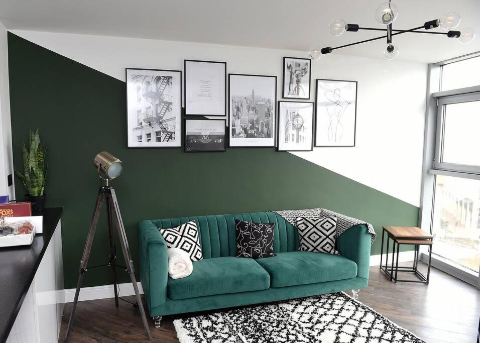 a green couch in a living room with pictures on the wall at Trendy city centre apartment with free parking in Cardiff