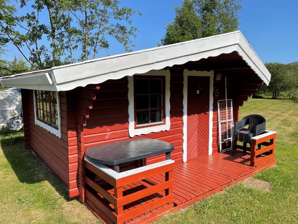 a red cabin with a porch and a grill at Bygholm Camping in Vesløs