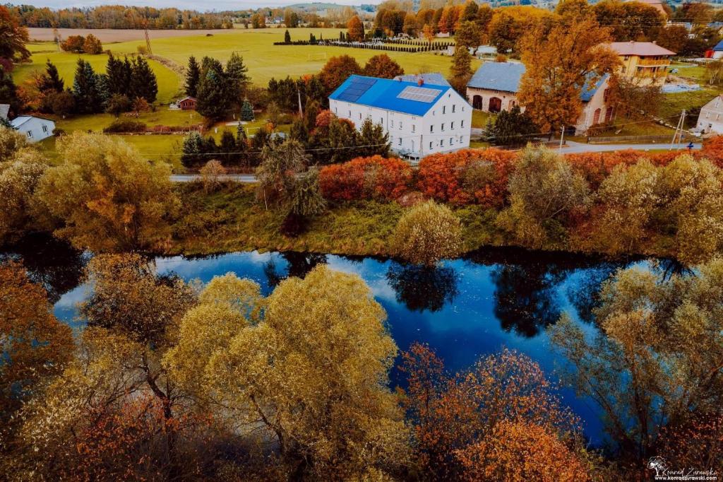 una vista de otoño de un edificio y un lago en Agroturystyka pod niebieskim dachem, en Siedlęcin