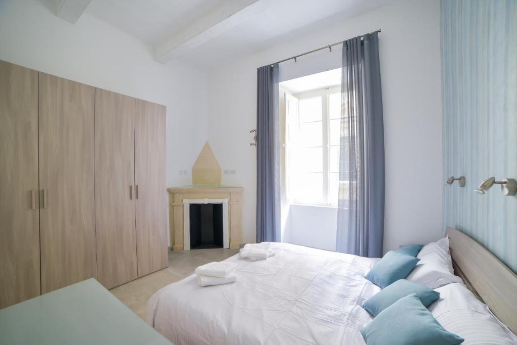 a bedroom with a large white bed with blue pillows at CA1- City Central Apartment 1 in Valletta