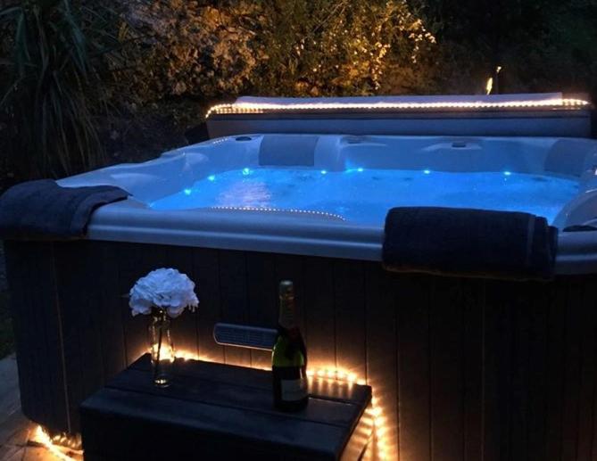 a hot tub with a bottle of wine and a flower at Birchwood Cottage with hot tub in Valley