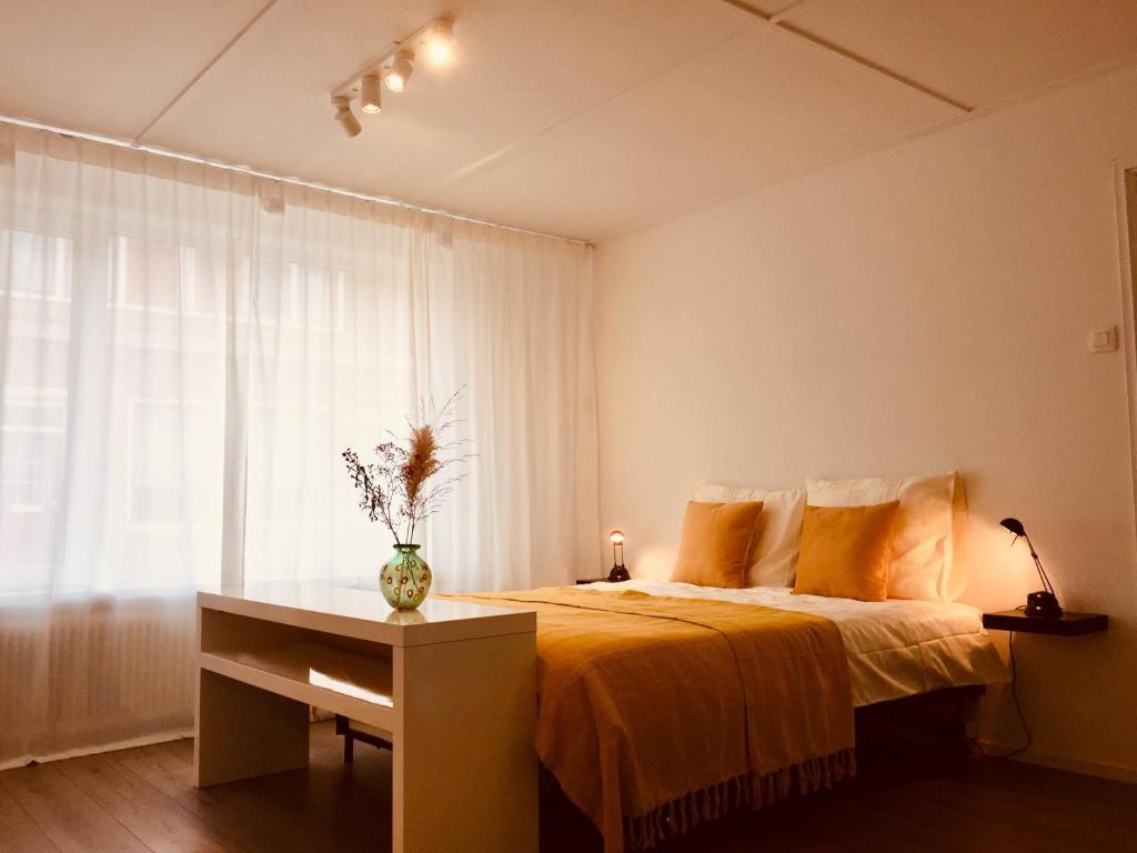 a bedroom with a bed with a yellow blanket and a window at Vakantiehuis vlakbij het strand en natuur in Biervliet