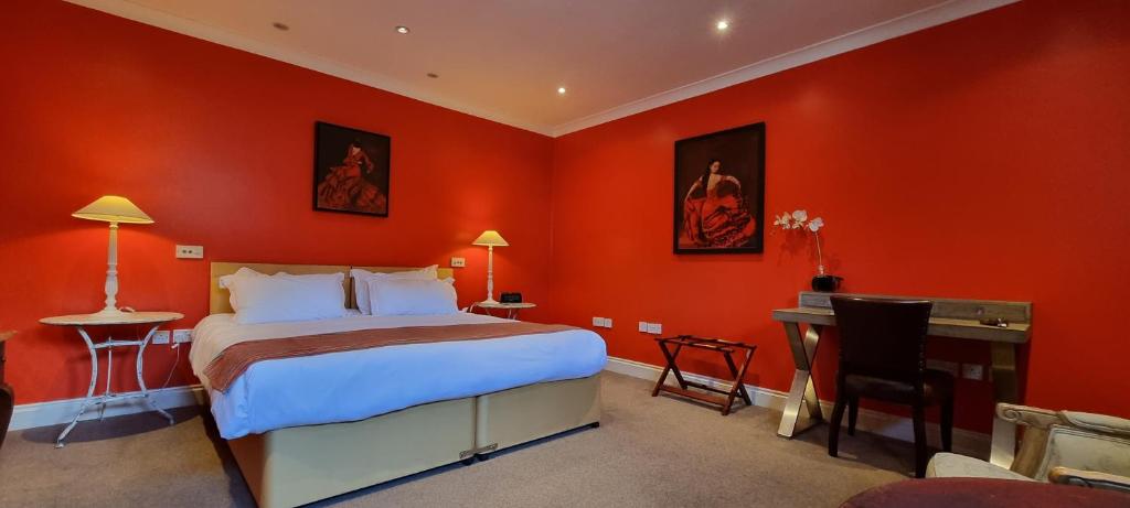 a bedroom with red walls and a bed and a desk at Buccleuch and Queensberry Arms Hotel in Thornhill