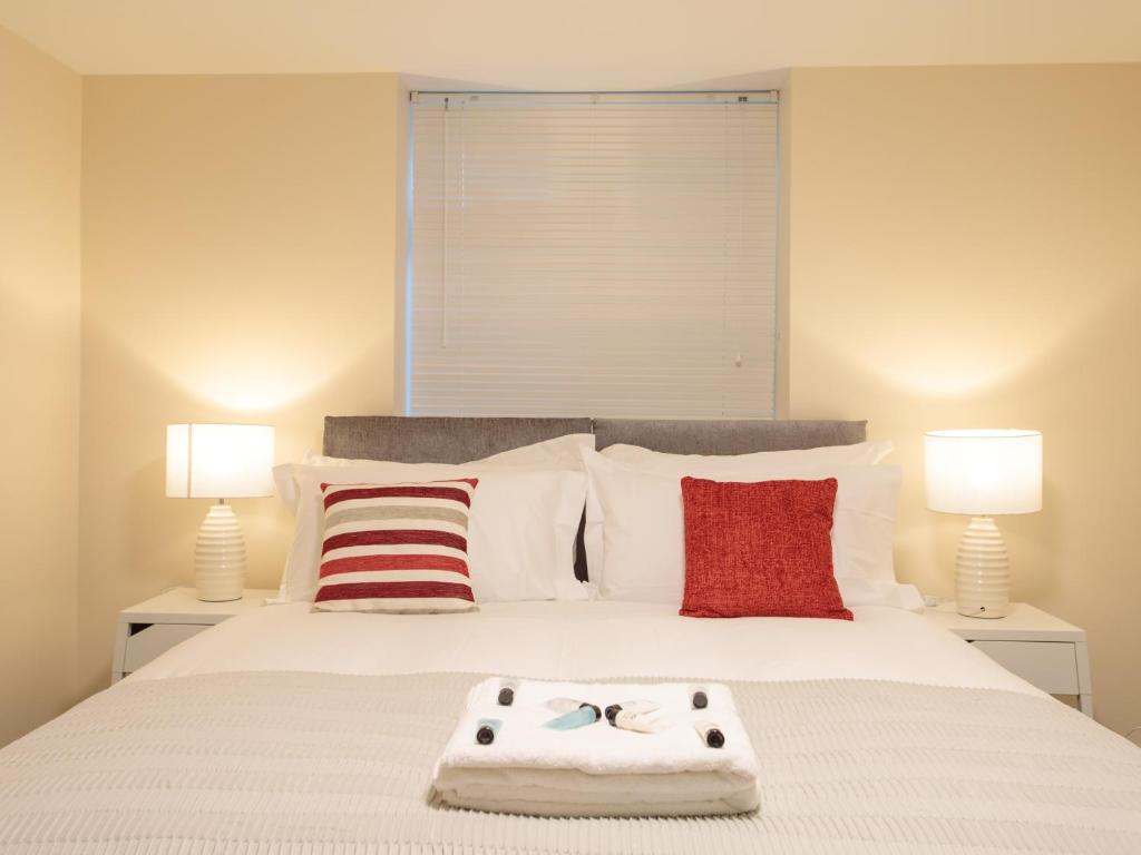 a bedroom with a large white bed with two lamps at Dartford Luxurious Apartment in Dartford