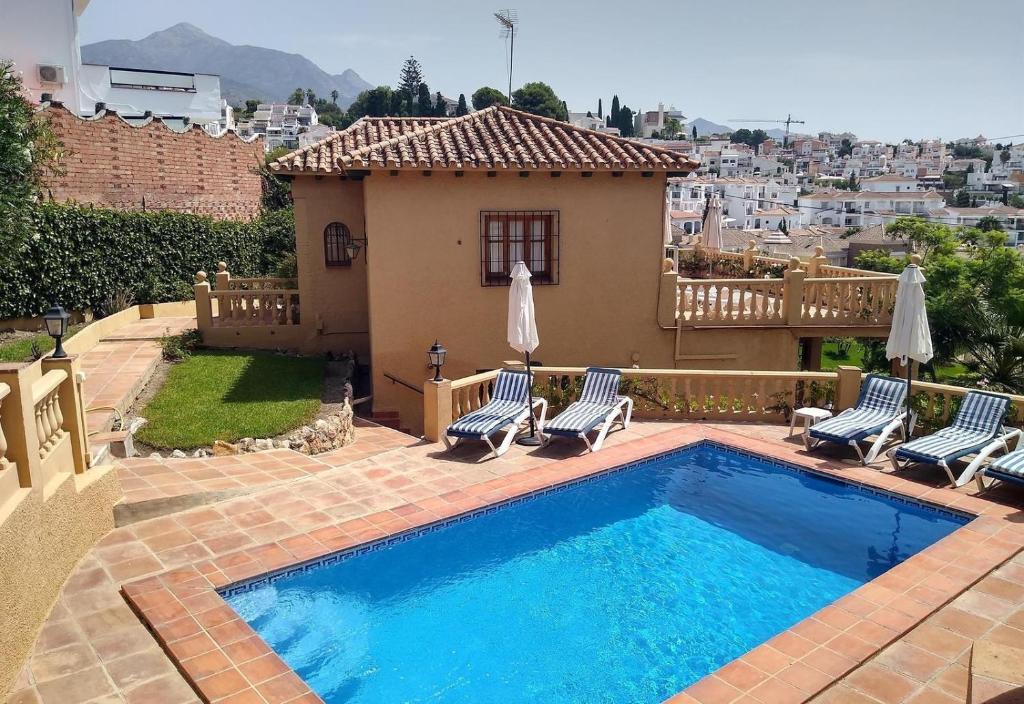 a swimming pool with chairs and a house at Unique villa with magnificent views in Nerja