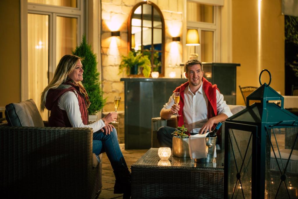 a man and a woman sitting at a table with drinks at Hotel Stenitzer in Bad Gleichenberg