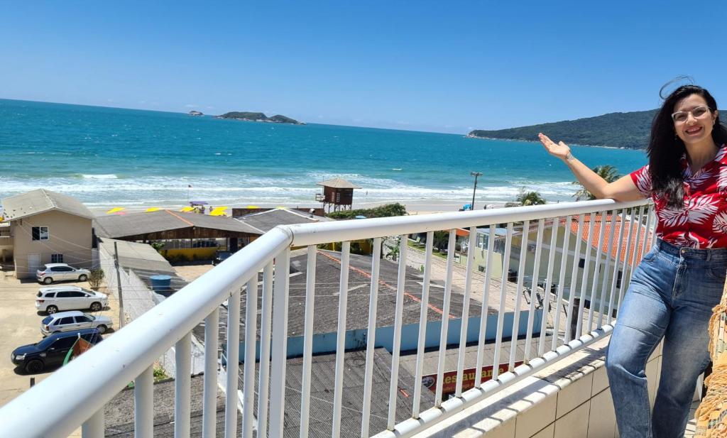 a woman standing on a balcony next to the beach at Praia Pousada Tatuíra in Florianópolis