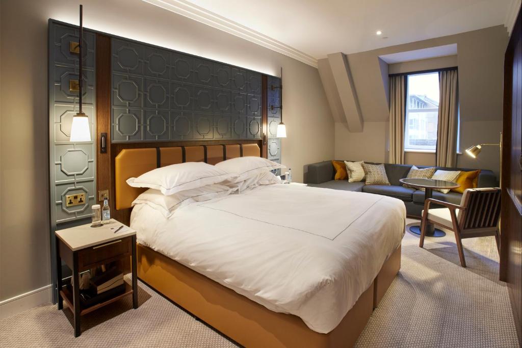 a bedroom with a large bed and a living room at The Parkgate Hotel in Cardiff