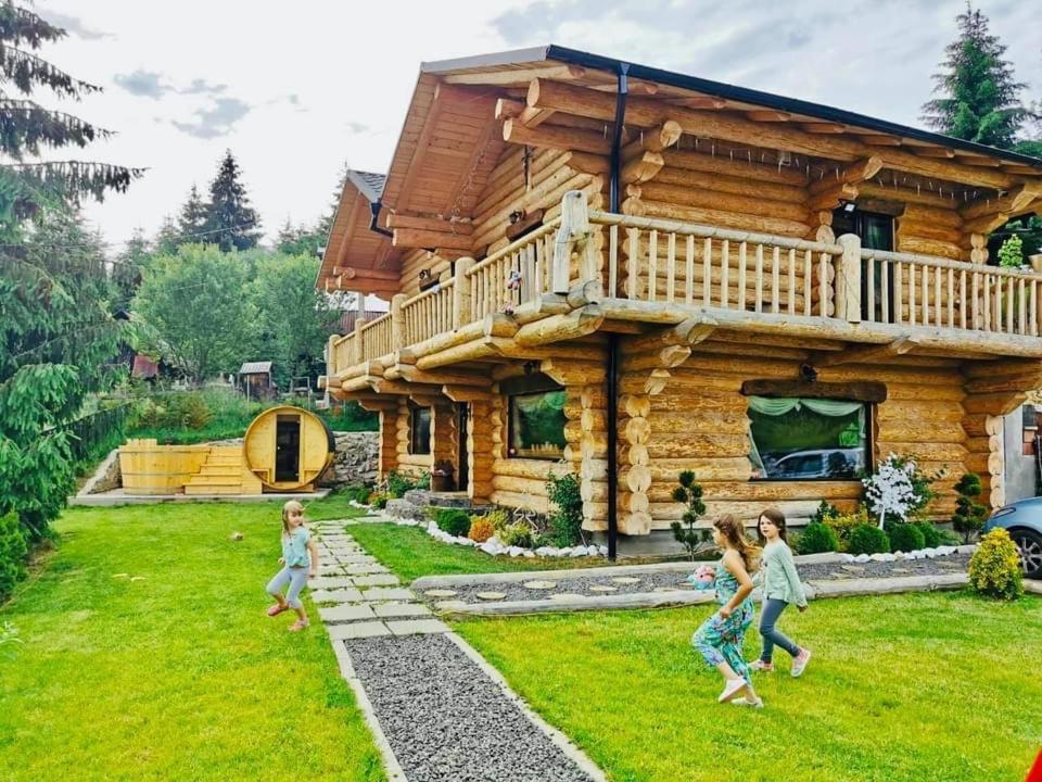 a family running in front of a log cabin at The Mountain's Sea Chalet in Colibiţa