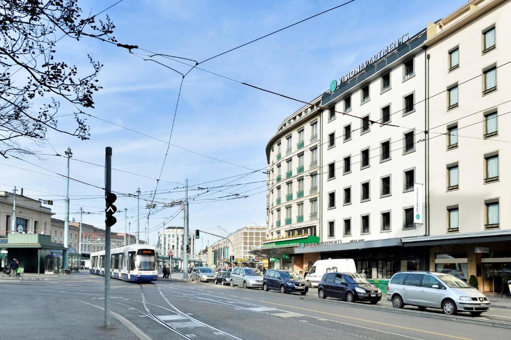 un tramway dans une rue de la ville avec des voitures et des bâtiments dans l'établissement VISIONAPARTMENTS Geneva Gare, à Genève