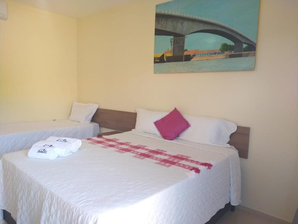 a bedroom with two beds with white sheets and pink pillows at Pousada Beira Rio Parnaíba in Parnaíba