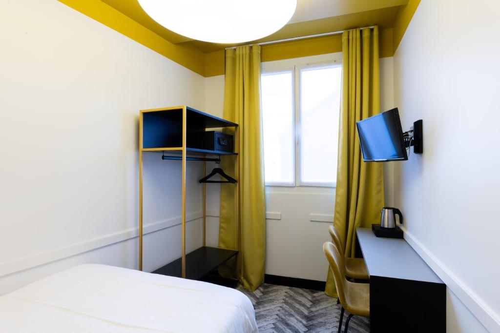 a room with a bed and a desk with a tv at Hôtel Gérando in Paris