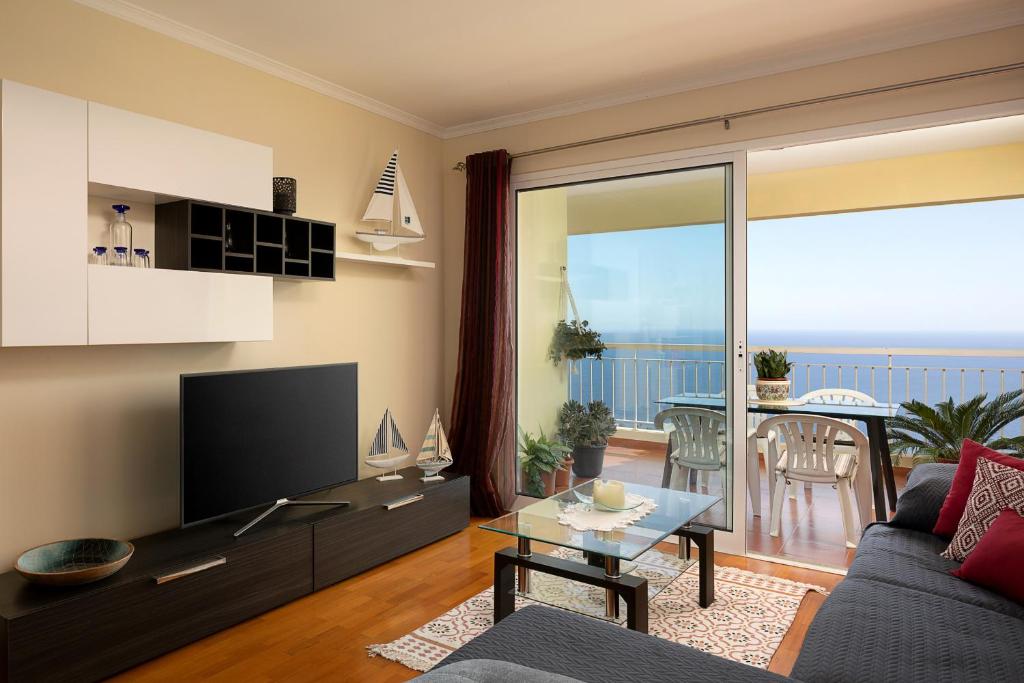 salon z kanapą i telewizorem oraz balkonem w obiekcie Wonderful Sea by Madeira Sun Travel w Caniço