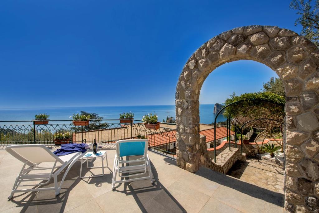 un patio con sillas y un arco con el océano en el fondo en Villa Marianna, en Massa Lubrense