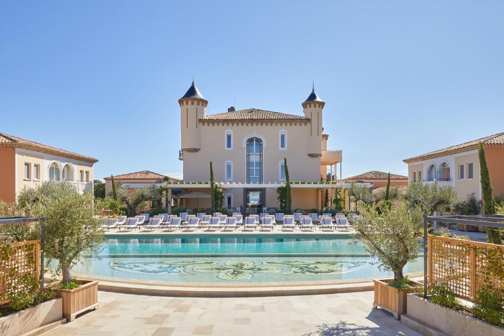 圣特罗佩Airelles Château de la Messardière的一座别墅,在一座建筑前设有一个游泳池