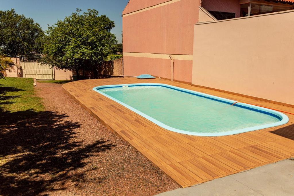 a swimming pool on a wooden deck next to a house at Chale c piscina e churrasqueira em Sao Leopoldo-RS in São Leopoldo