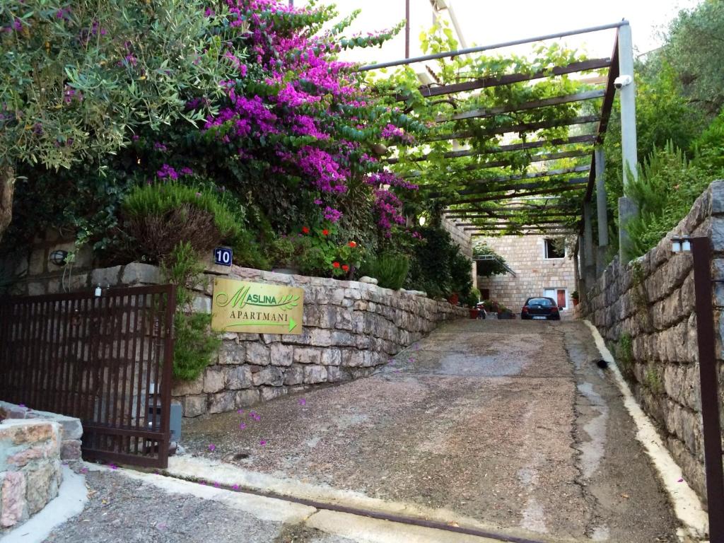 a garden with a stone fence and purple flowers at Guest House Maslina in Petrovac na Moru