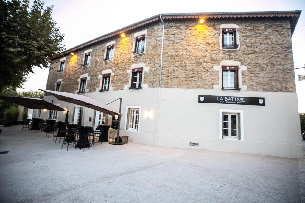 un gran edificio de ladrillo con mesas y sillas delante de él en Hôtel La Batisse, en Crémieu