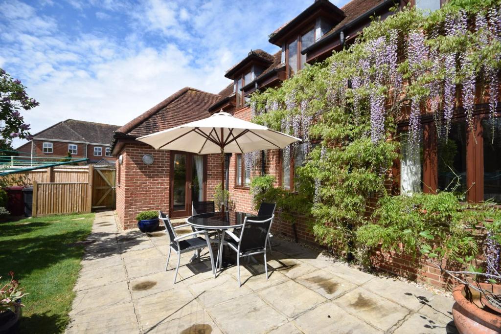 a patio with a table and chairs and an umbrella at Wisteria Way, Tangmere in Tangmere