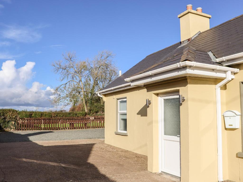 una casa con una puerta blanca y una valla en Lane Cottage 