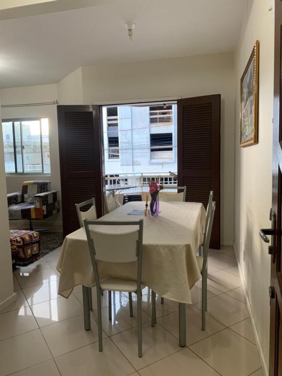 a dining room with a white table and chairs at Apto lindo e aconchegante próximo a praia in Itapema