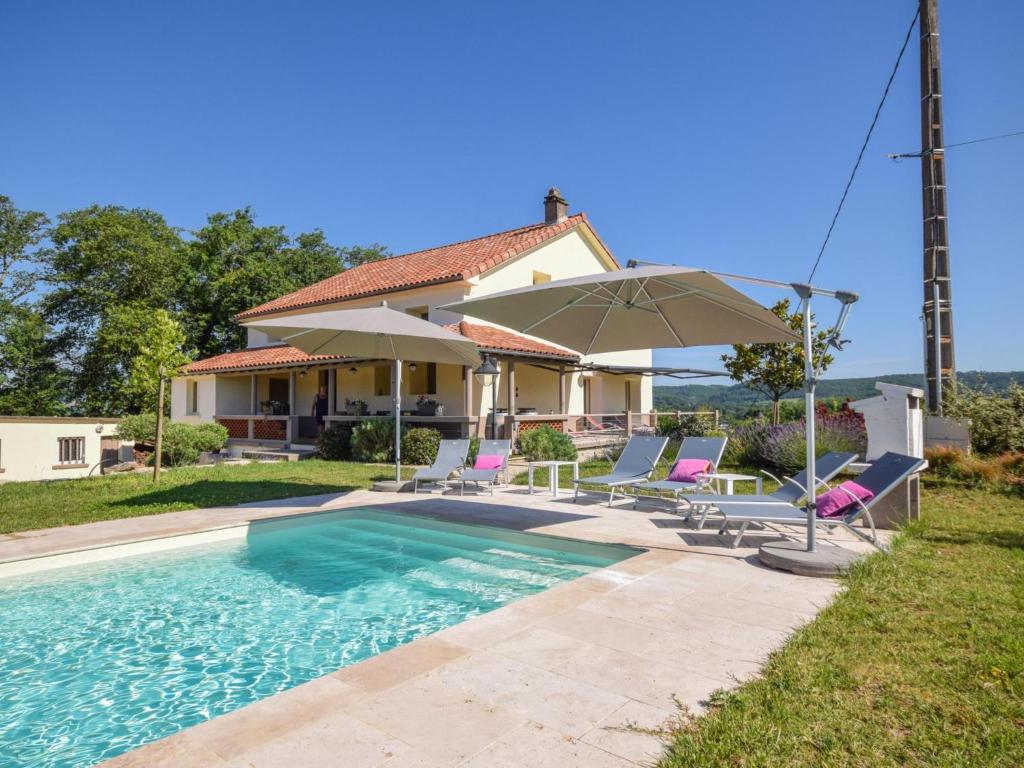 uma casa com uma piscina com cadeiras e um guarda-sol em Villa la Fontaine em Viré