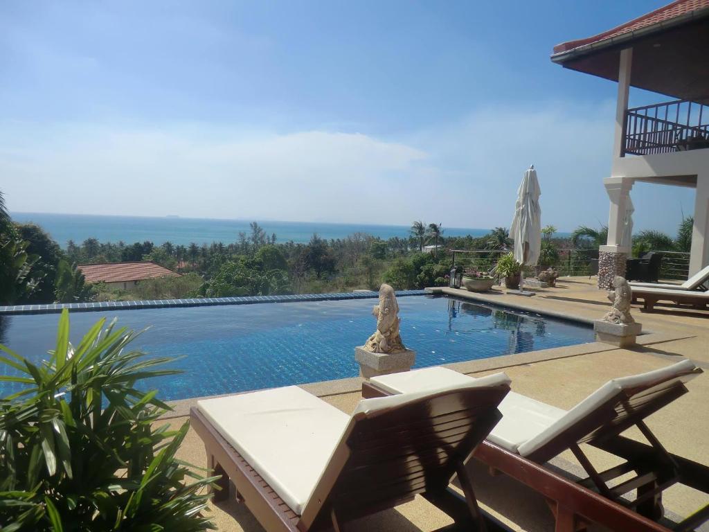 a swimming pool with two lounge chairs next to a house at Amazing Seaview Villa in Ko Lanta