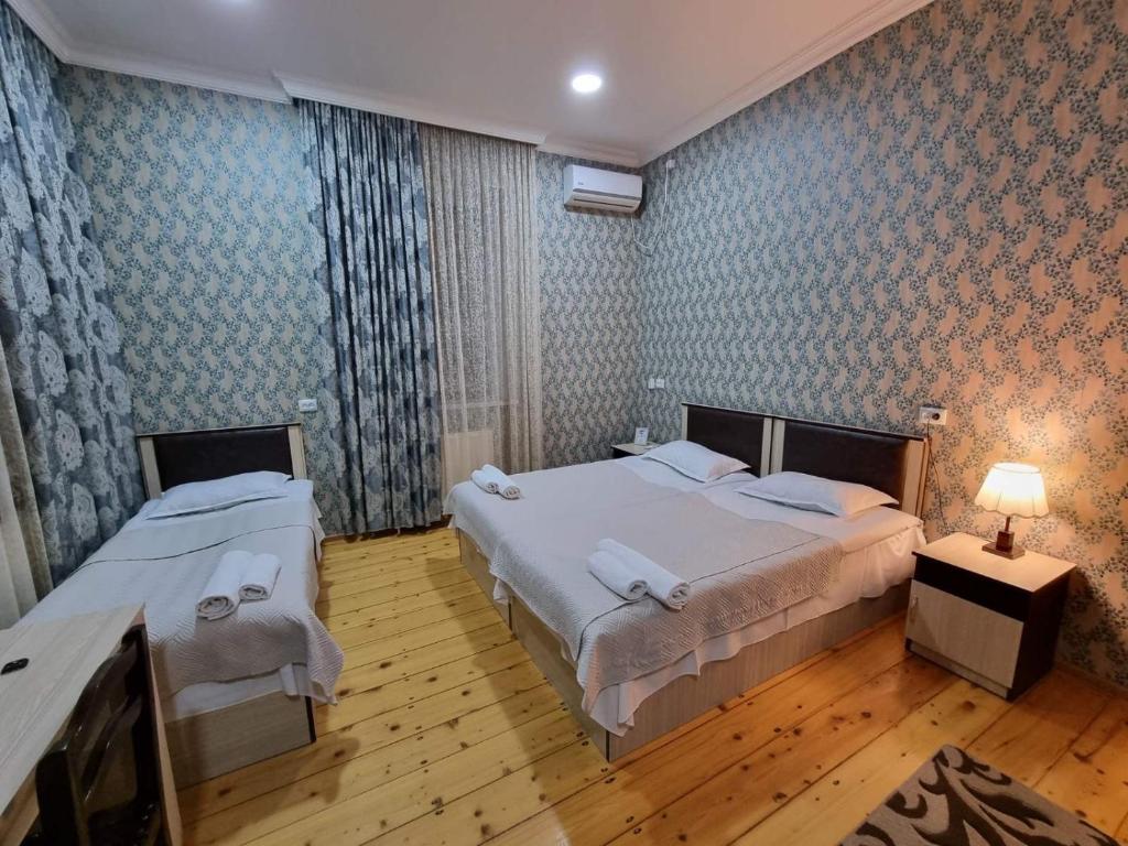 een slaapkamer met 2 bedden en een tafel met een lamp bij HOTEL JULIA Akhaltsikhe in Akhaltsikhe