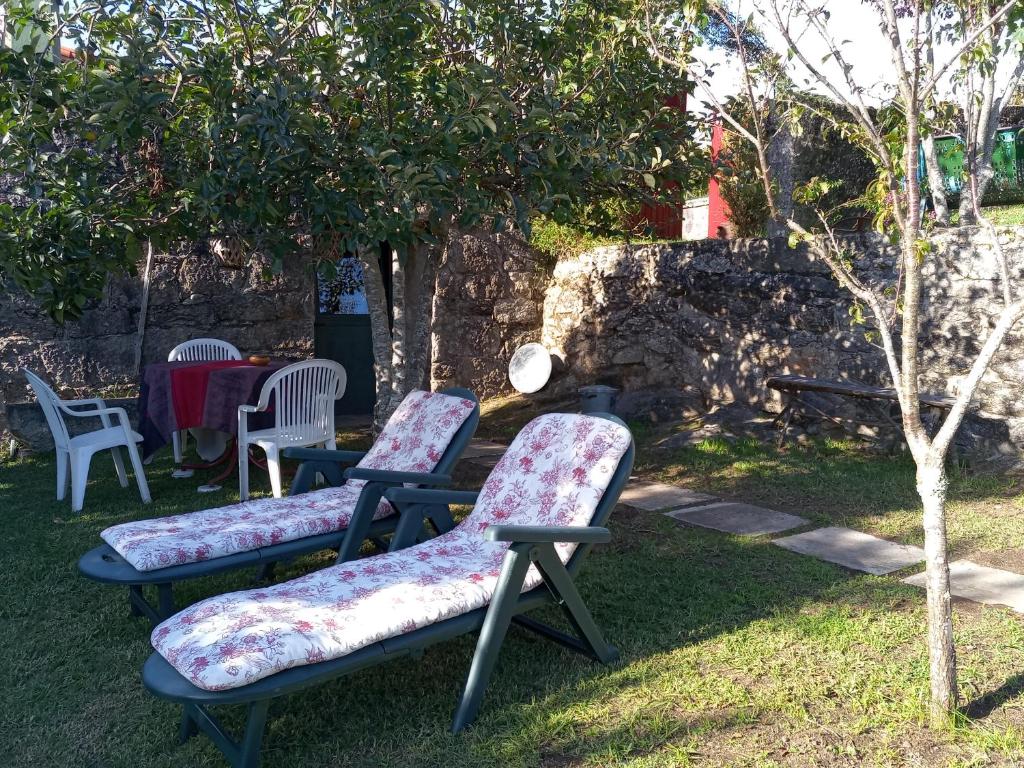 three chairs with floral cushions sitting in a garden at Casa Lameiro Redondela in Redondela