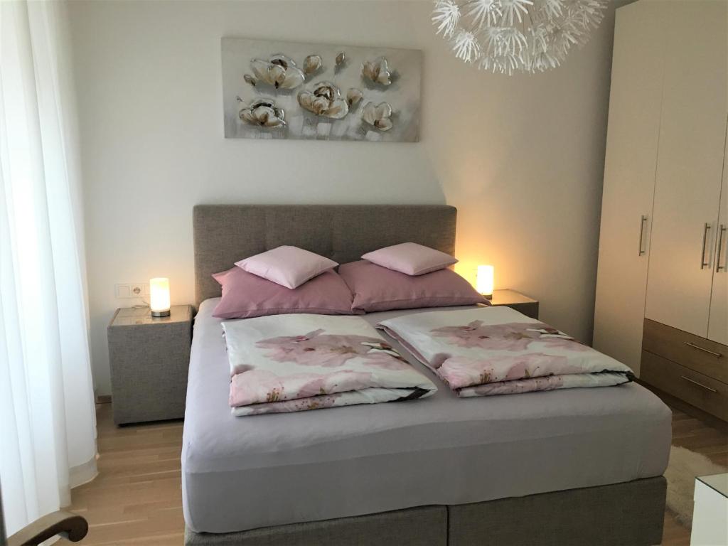um quarto com uma cama com almofadas cor-de-rosa e um lustre em Ferienwohnung DANUBIA em Linz