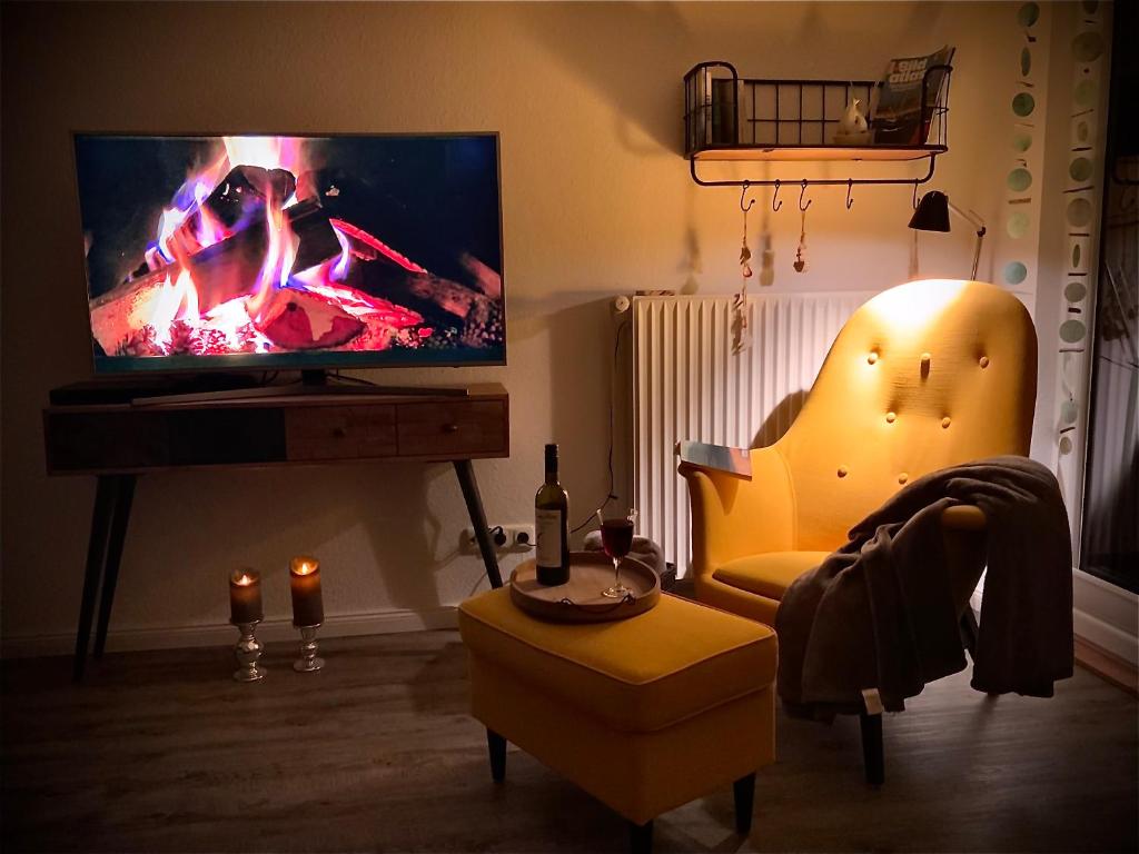 ein Wohnzimmer mit Fernseher und einem Sessel mit Kamin in der Unterkunft Nordbrise in Büsum