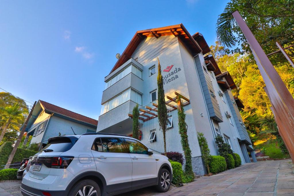 um carro branco estacionado em frente a um edifício em Pousada Viena em Gramado