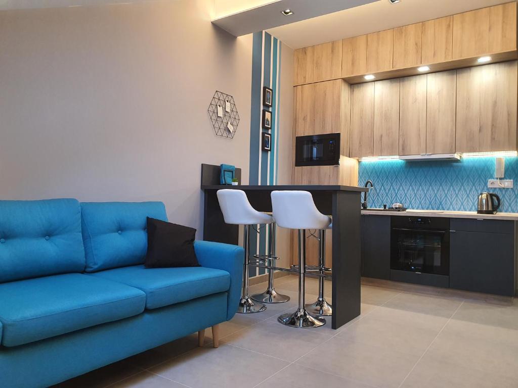 a living room with a blue couch and a kitchen at Kaposvár Apartman in Kaposvár