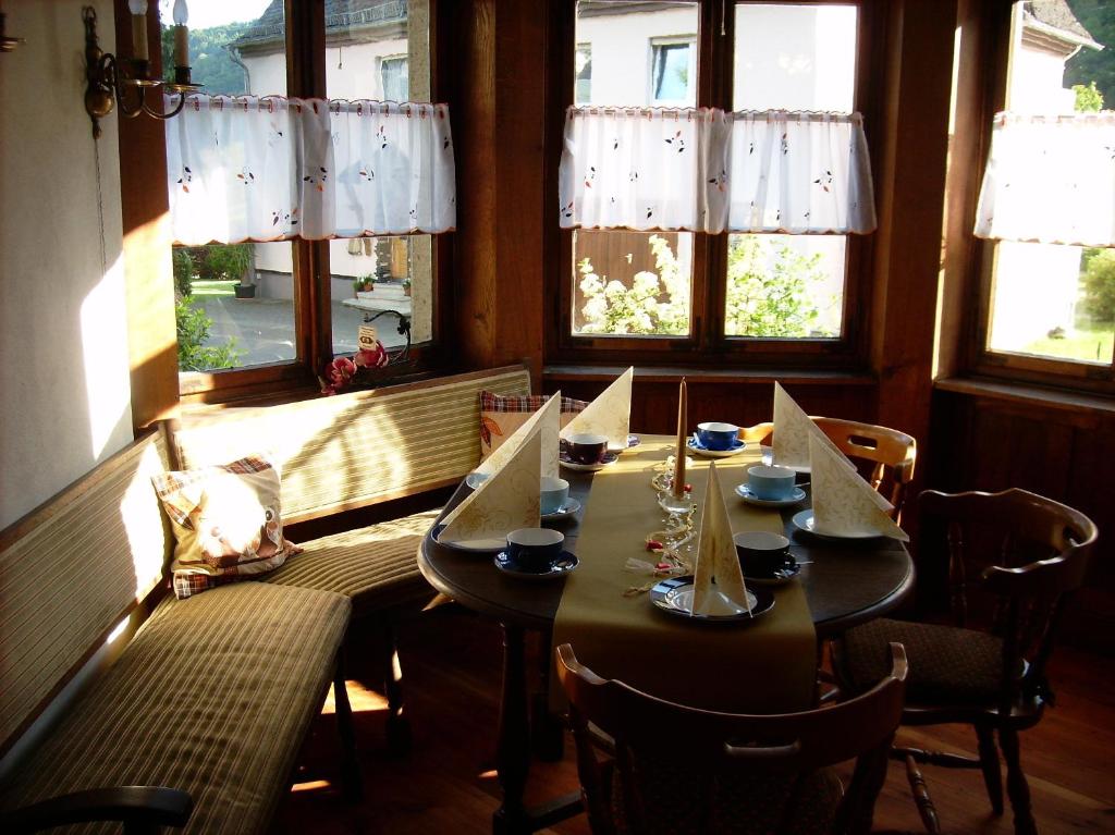 a dining room with a table and chairs and windows at Moselvilla Enkirch in Enkirch