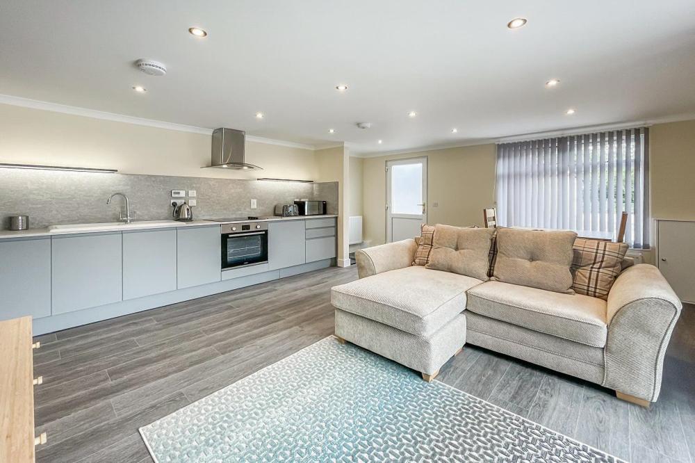 uma sala de estar com um sofá e uma cozinha em Barra Cottage em Ballachulish