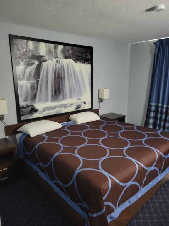 a hotel room with a bed with a picture of a waterfall at Super 8 North Red Deer in Red Deer