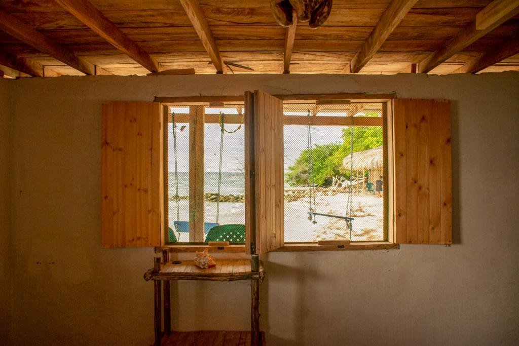 - une fenêtre dans une chambre avec vue sur la plage dans l'établissement Dahlandia, à Isla Mucura