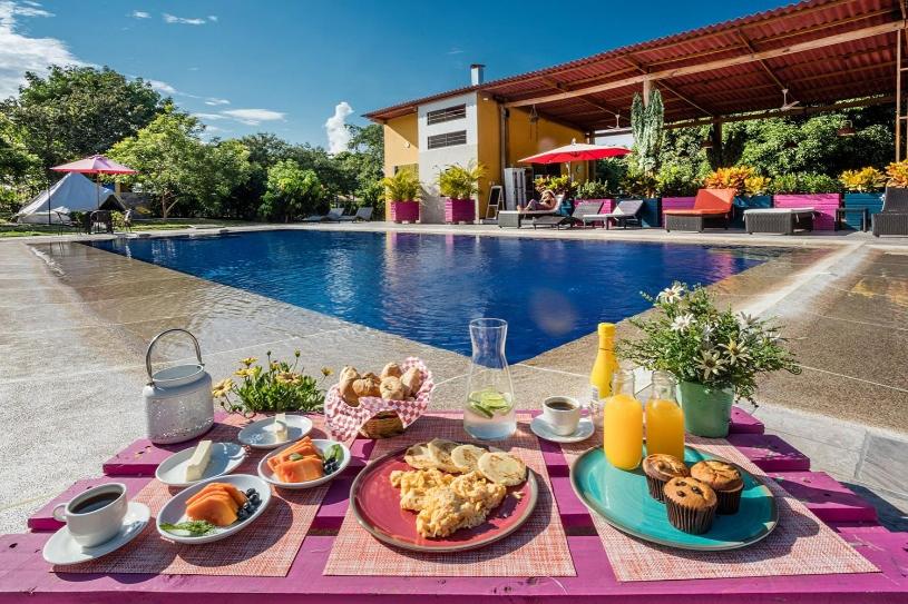 a table with food and drinks next to a pool at Mangoo Glamping in Melgar