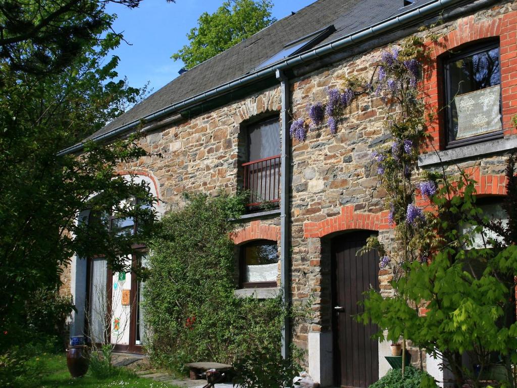une vieille maison en briques avec des fleurs sur le côté dans l'établissement Gite Panda La Sylve, à Tenneville