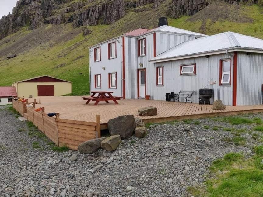Casa con terraza de madera frente a una montaña en Guesthouse Stekkatún, en Skálafell