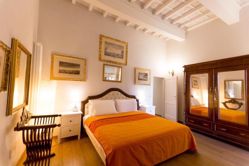 a bedroom with a bed with an orange bedspread at Borgo Pinti Suites Le Stanze dei Nobili in Florence