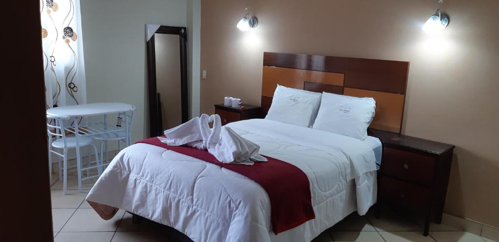 a bedroom with a bed with white sheets and a chair at Hotel Alpamayo Cajamarca in Cajamarca