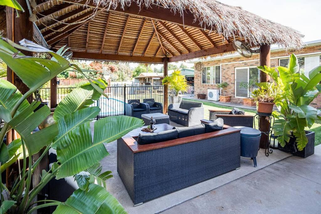 un patio con sofás y sillas bajo un pabellón en Apartment Bali Style with Pool and Fire Pits, en Parkes
