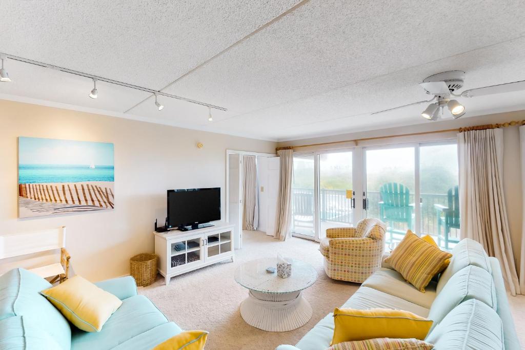 a living room with a blue couch and a tv at Nauti by Nature in Nags Head