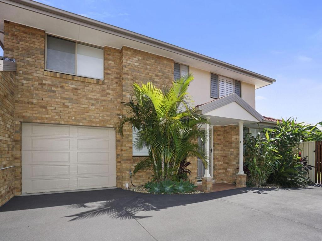 a brick house with a garage and palm trees at 44 Oaks Avenue in Long Jetty