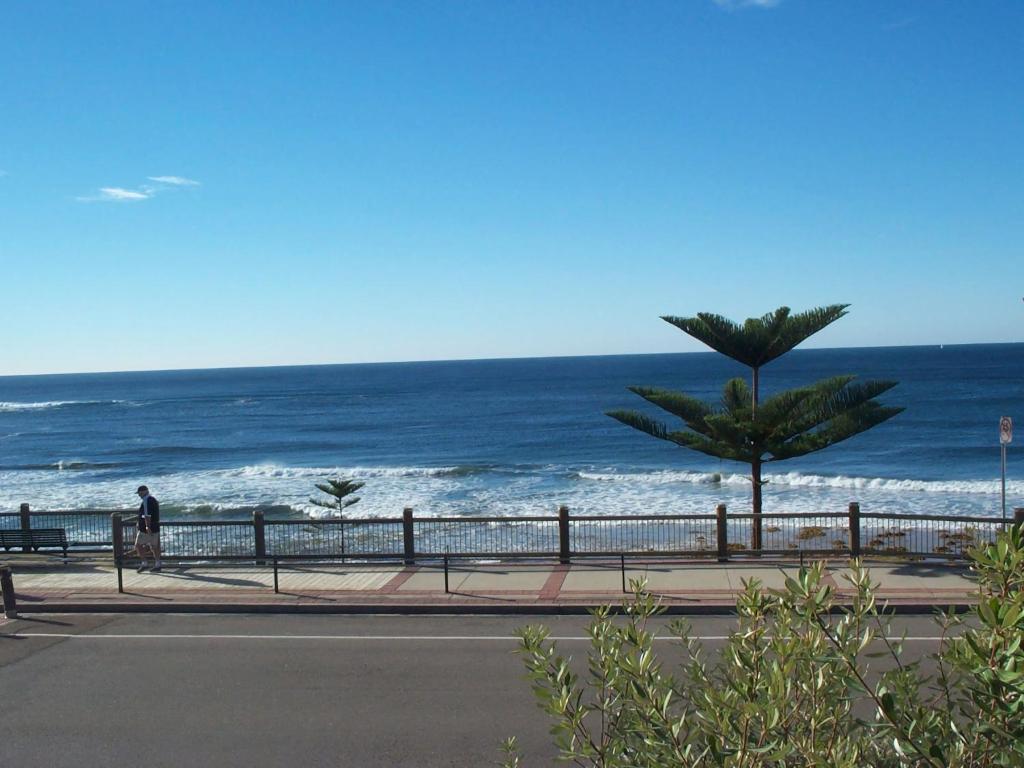 a person walking on a sidewalk next to the ocean at Calypso, Unit 1 - The Entrance, NSW in The Entrance