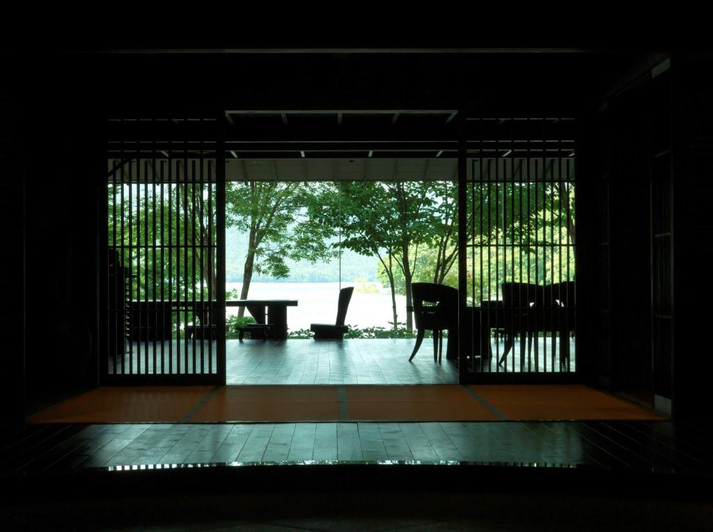 eine offene Tür zu einer Terrasse mit einem Tisch und Stühlen in der Unterkunft Akan Tsuruga Besso Hinanoza in Akankohan
