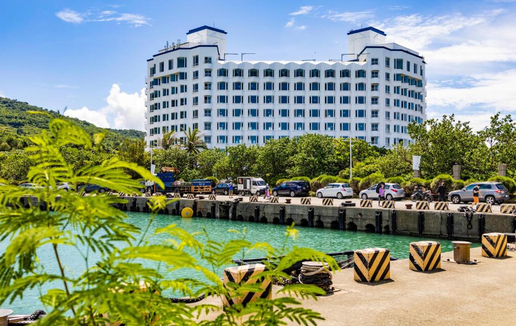 a large white building with chairs in front of a body of water at Kenting Long Beach Hotel in Checheng