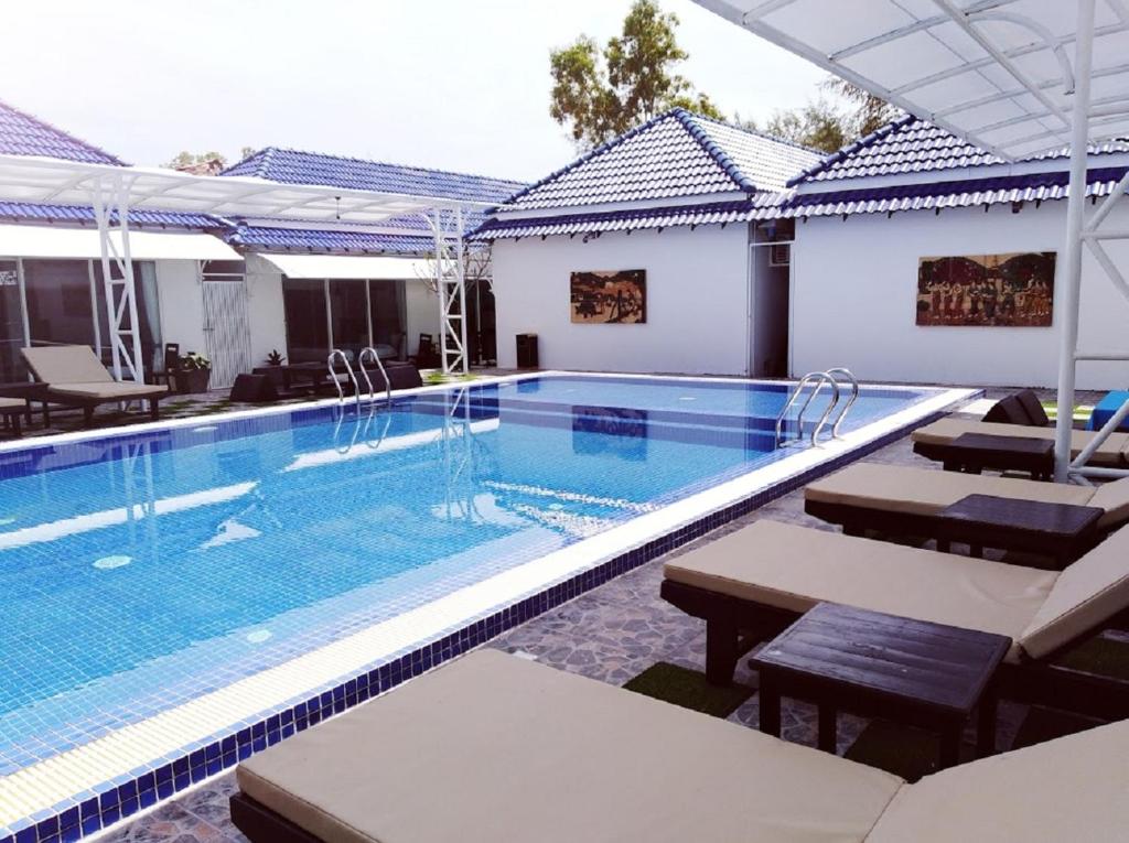 una piscina en un hotel con mesas y sillas en Good Time Boutique Hotel, en Sihanoukville