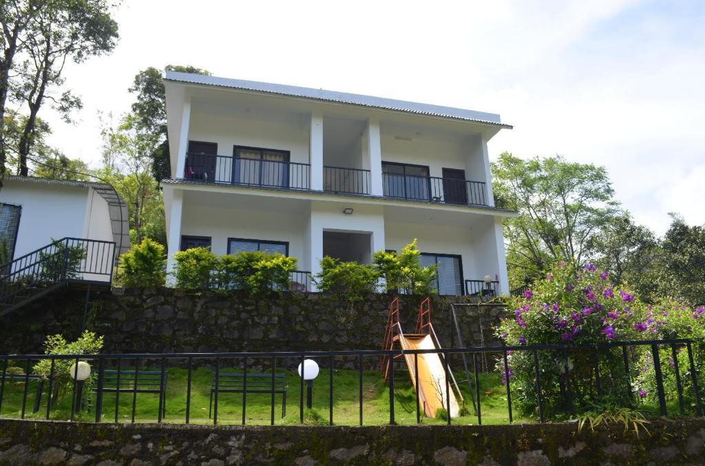 a white house with a fence in front of it at Mist WOODS VAGAMON in Vagamon